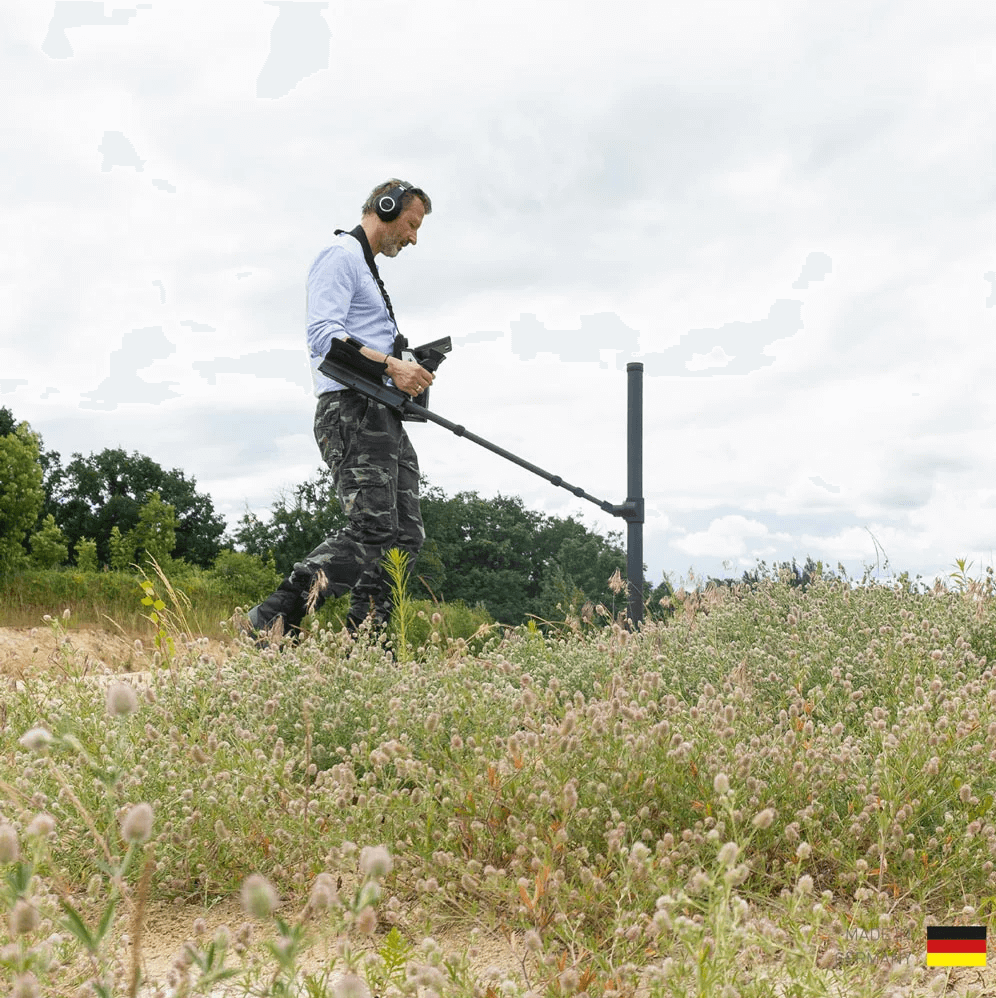 A man in a field using the OKM eXp 6000 Professional metal detector