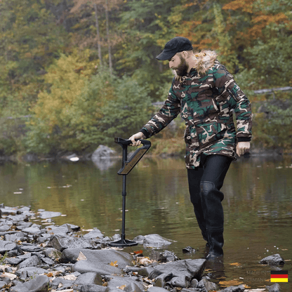 A man using the OKM Evolution NTX to ground scan in a riverbed